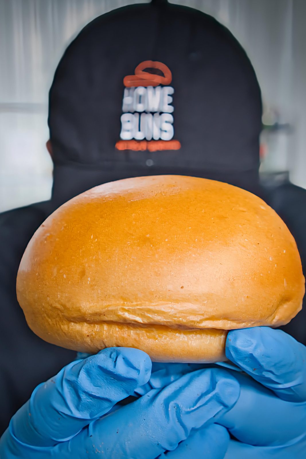 Colaborador con gorra Home Buns sosteniendo un pan de hamburguesa